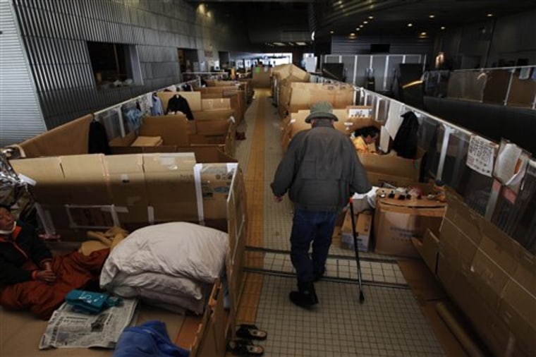 A man walks between spaces for families, divided by corrugated boxes, at the evacuation center at the Big Palette Fukushima sports arena in Koriyama, Japan, April 12.